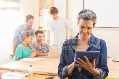 Businesswoman using a tablet with colleagues behind