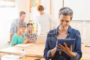Businesswoman using a tablet with colleagues behind