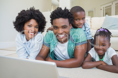 Happy family lying on the floor using laptop