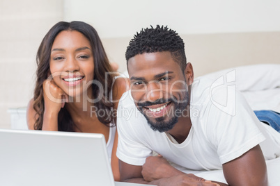 Relaxed couple using laptop on bed