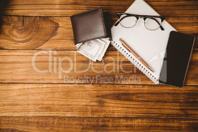Pen and glasses on notepad next to wallet and smartphone
