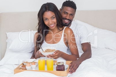 Relaxed couple having breakfast in bed together