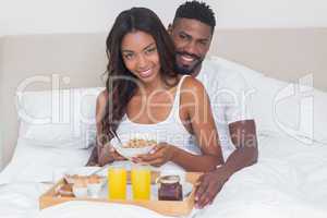 Relaxed couple having breakfast in bed together