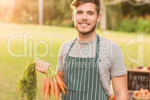 Handsome farmer holding carrots