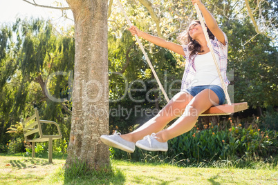 Pretty brunette swinging in park