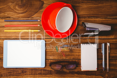 Tablet next to cup and notepad