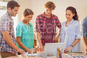 Happy creative business team using laptop in meeting