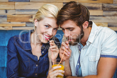 Cute couple on a date sharing a glass of orange juice