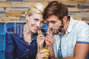 Cute couple on a date sharing a glass of orange juice