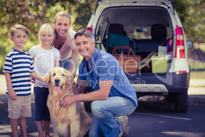 Happy family smiling at the camera with their dog