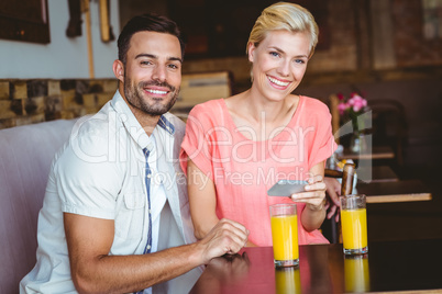 Cute couple sitting in cafe looking at smartphone