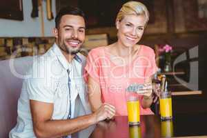 Cute couple sitting in cafe looking at smartphone