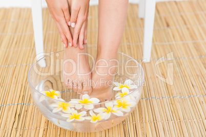 woman washing her feet in a bowl of flower