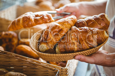 happy worker holding a basket of croissant