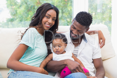 Happy couple with their baby girl on couch