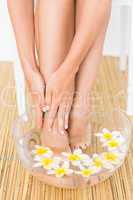 woman washing her feet in a bowl of flower