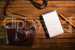 Notepad next to camera and pen