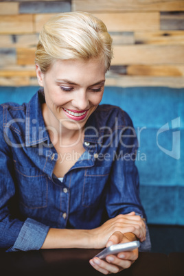 Smiling pretty blonde sending a text message