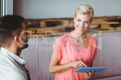 Smiling blonde woman using tablet and looking her boyfriend