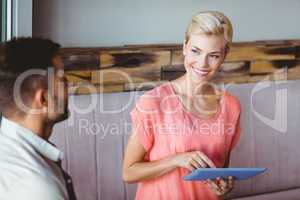 Smiling blonde woman using tablet and looking her boyfriend