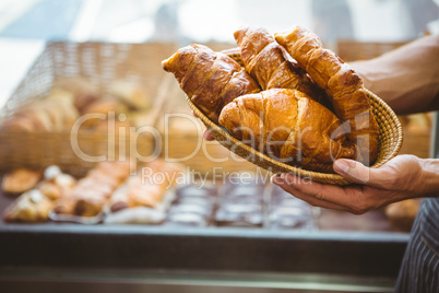 happy worker holding a basket of croissant