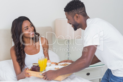 Relaxed couple having breakfast in bed together