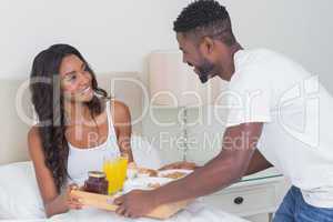 Relaxed couple having breakfast in bed together