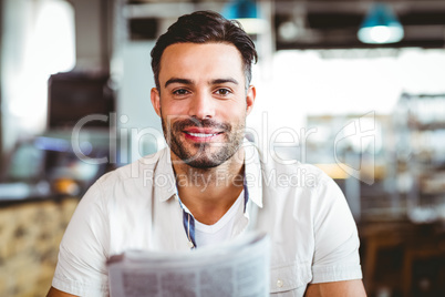 Young man having cup of coffee reading newspaper