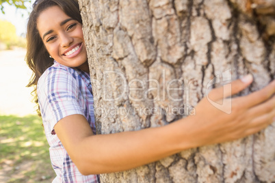 Pretty brunette hugging tree