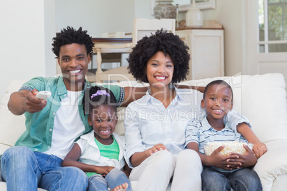 Happy family watching television eating popcorn