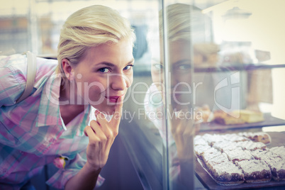 Hesitating pretty woman looking at cup cakes