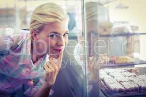 Hesitating pretty woman looking at cup cakes