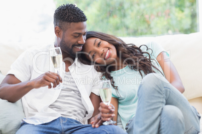 Happy couple on the couch having champagne