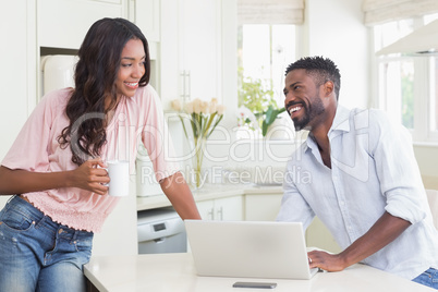 Happy couple using their laptop at breakfast