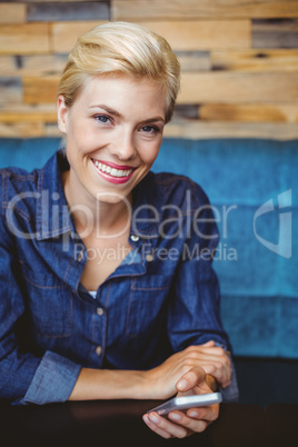Smiling pretty blonde sending a text message