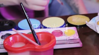 Woman draws with watercolors at the table