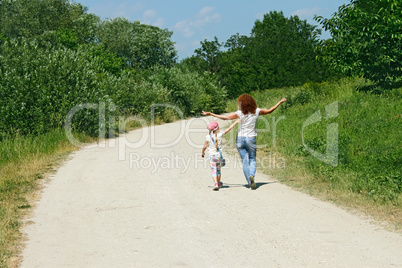 Mother and daughter walking by rural road