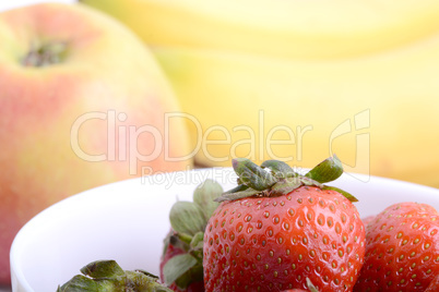Fruits. Arrangement of various fresh ripe fruits: bananas, apple and strawberries closeup