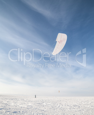 Kiteboarder with blue kite on the snow