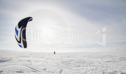 Kiteboarder with blue kite on the snow