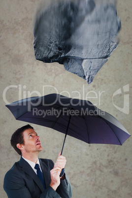 Composite image of businessman sheltering under black umbrella