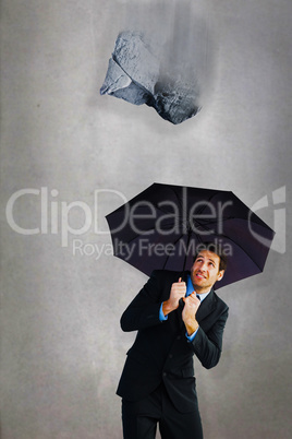 Composite image of businessman sheltering with black umbrella