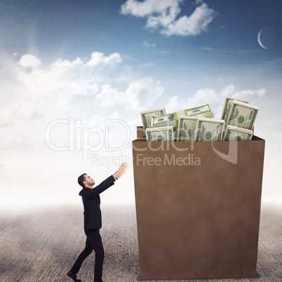 Composite image of businessman with arms raised catching somethi