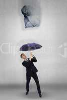 Composite image of businessman standing under black umbrella
