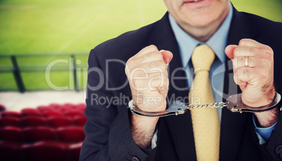 Composite image of closeup of businessman with handcuffed hands
