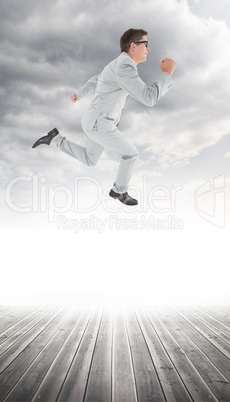 Composite image of geeky happy businessman running mid air