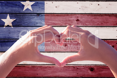 Composite image of hands making heart shape on the beach