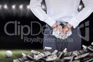 Composite image of businessman in handcuffs holding bribe