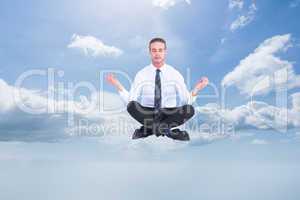 Composite image of businessman meditating in lotus pose