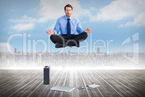 Composite image of man sitting in lotus pose with laptop tablet